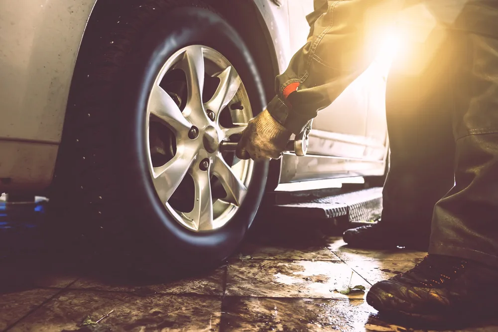 Mechanikas veržia automobilio rato varžtus servise